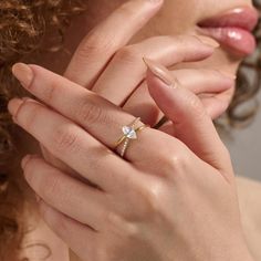 a close up of a person wearing a gold ring with a diamond on the middle