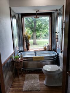 a bath tub sitting next to a window in a bathroom under a large window sill