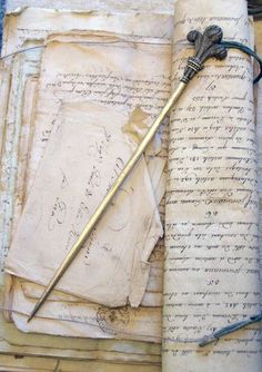 an old book with writing on it and a long metal stick sticking out of the pages