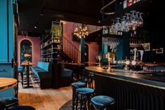 the interior of a bar with stools, tables and chandeliers hanging from the ceiling