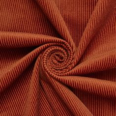 a close up view of an orange corded fabric with a circular design on it