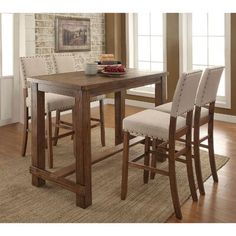 a dining room table with four chairs and a bowl of fruit on the counter top