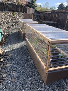 an outdoor garden area with gravel, rocks and wooden fenced in areas that have plants growing out of them