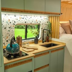 a kitchen with a tea kettle on the counter and a window in the back ground