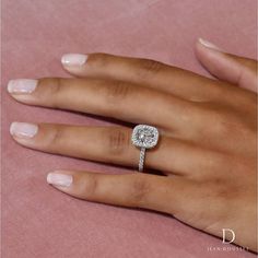 a woman's hand with a diamond ring on top of her finger and pink background