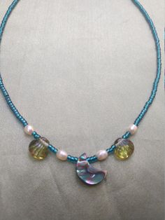 This delicate necklace has a oceany feeling. The pendent is made of abalone shell and is accented with white pearls and glass beads. Little blue seed beads bring it all together for a watery look. And it is finished off with a sterling silver  heart clasp. Handmade Blue Pendant Pearl Necklace, Handmade Blue Pearl Pendant Necklace, Blue Beaded Necklaces With Pearl Pendant, Blue Beaded Necklace With Pearl Pendant, Blue Beaded Pearl Necklaces With Pearl Pendant, Blue Beaded Necklace With Pearl Drop For Gift, Celestial Blue Beaded Necklaces, Blue Shell Beaded Necklaces, Abalone Shell Beaded Necklaces As Gift