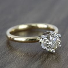 a diamond engagement ring sitting on top of a wooden table