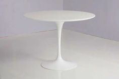 a white table sitting on top of a white floor next to a purple and white wall