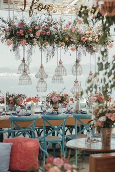 an outdoor dining area with blue chairs and flowers hanging from the ceiling