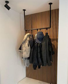 a coat rack with hats and coats hanging from it's sides in front of a striped wall