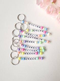 four keychains with words written on them sitting next to flowers and a pink flower