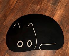 a black cat shaped floor mat sitting on top of a wooden floor