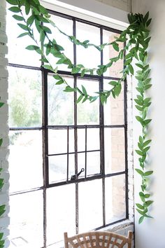 a chair sitting next to a window covered in green leaves