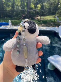 a person holding a small stuffed animal with beads on it's neck and wearing a necklace