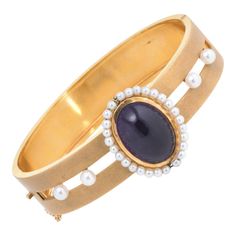 Finely detailed vintage Art Deco era bangle (circa 1920s to 1930s), crafted in 14k yellow gold.   Cabochon cut amethyst measures 17mm x 12mm (estimated at 11.50 carats), accented with 28 x 2.25mm seed pearls and a further 4 x 4mm cultured pearls. The pearls are well matching, lustrous and show rose overtones. The amethyst is in excellent condition and free of cracks or crisps.   The bracelet features a satin finish with a lovely muted gold effect. The statement bracelet is great worn alone or la Pearl Bangle Bracelet, Pearl Bangle, Bracelet Vintage, Art Deco Era, Statement Bracelet, Cultured Pearls, Vintage Art Deco, Vintage Art, Metallica