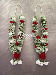 two red and white flowers are hanging from the side of each other on a gray background