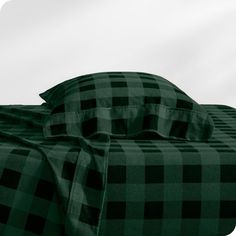 a black and green plaid bedspread on a bed with pillows in the background