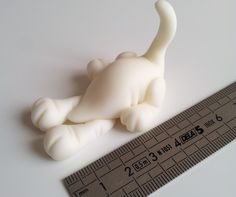 a plastic toy cat laying on top of a measuring tape next to it's body