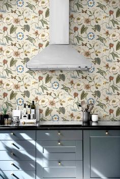 a stove top oven sitting inside of a kitchen next to a wallpapered wall