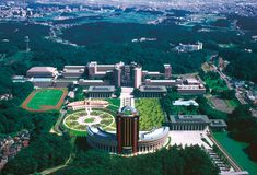 an aerial view of a large building in the middle of trees and buildings around it