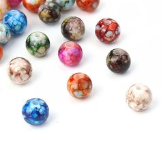 several different colored glass beads on a white surface