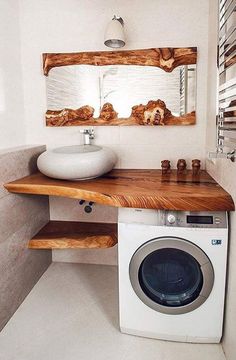 a washer and dryer in a bathroom with wooden shelves on the wall above it