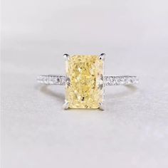 a fancy yellow diamond ring with two diamonds on the band and side stones around it