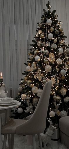 a decorated christmas tree with white and silver ornaments in the corner next to a dining room table