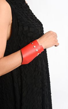 Red Oversize Cuff - METBR3 An extraordinary leather bracelet for people who simply adore accessories. This wide wristband is handmade of a special pattern leather in gorgeous red color. The leather had beed professionally processed in order to have a more interesting look. There is a line of studs on one side of the bracelet making it modern and daring while the lower part is asymmetrical. The bracelet is about 10 inches / 25 cm long and it closes with a snap button. NOTE! Since every piece is e Adjustable Leather Cuff Bracelet For Party, Adjustable Wrist Strap Wristlet For Party, Adjustable Wristlet With Wrist Strap For Party, Trendy Red Bracelets For Party, Leather Cuff Bracelets For Party, Handmade Adjustable Red Leather Bracelet, Handmade Red Leather Bracelet, Adjustable Red Cuff Bracelet As Gift, Adjustable Red Leather Strap Bracelet