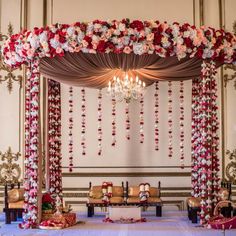 a decorated wedding stage with flowers and chandelier hanging from it's ceiling