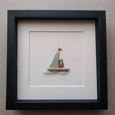 a small sailboat with two people on it in a black framed art print frame