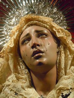 a statue of a woman wearing a headdress with tear drops on her face