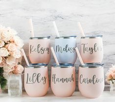 six pink and blue tumblers sitting on top of a white counter next to flowers