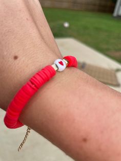 a person wearing a red bracelet with a cat in the hat bead on it