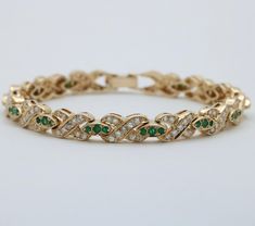 Fiery diamonds and vibrant emeralds are combined in this romantic XO design bracelet modeled in gleaming 14K gold.  Each of the X links are set with diamonds weighing a total of approximately 3.5 carats, mostly G/H/I in color and SI in clarity.  The "O" links are set with emeralds weighing approximately 1.44 carats.  Solidly constructed, this bracelet weighs 20 grams and measures 6.8 inches long.  A gorgeous piece to add to any jewelry collection! Metal: 14K Yellow Gold (acid tested) Weight: 20 grams Diamonds: Approx. 3.5 cts Emeralds: Approx. 1.44 cts Measurements: 6.8 inches by 6.5 mm wide  Markings: None Condition: In good vintage condition with some surface wear to a few emeralds.  Some diamonds appear to have been replaced later.  Follow us on Instagram @alphaomegajewelry for the late Gold Arm Band, Xo Design, Design Bracelet, Gold Armband, Long A, G H, Chain Link Bracelet, Bracelet Designs, Arm Band