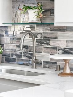 a kitchen sink and counter top with tile on the backsplash, above which is a potted plant