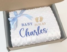 a baby blanket in a box with the name and foot prints on it that says, baby charles