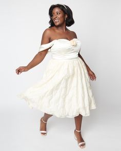 a woman in a white dress posing for the camera with her hands on her hips