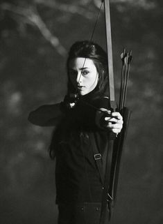 black and white photograph of a woman holding a bow with two arrows in her hands