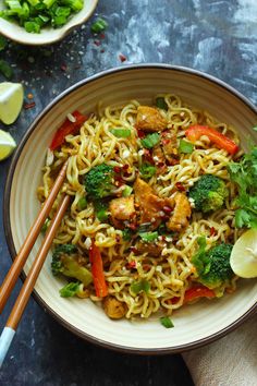 a bowl filled with noodles and vegetables next to chopsticks