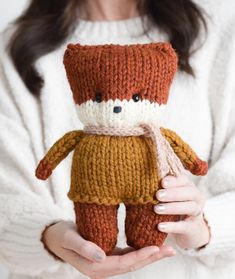 a woman holding a knitted teddy bear in her hands