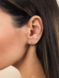 a woman wearing two different ear piercings on her left ear and the other one has a diamond in it