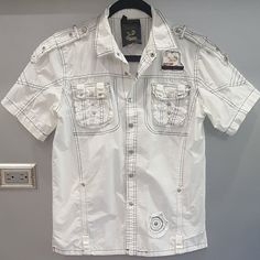 Super Cool & Edgy Distressed White Shirt! Very Well Made And Tailored. They Don't Make Shirts Like That Anymore! Designed With Western-Style Embellishments, Snap Buttons, Logos, Front Pockets, Black Contrast Stitching, And A Relaxed Fit. Versatile, Will Look Amazing With Any Outfit. Very Comfy, Made Of High-Quality Sturdy Yet Breathable 100% Cotton Treated To Create Superb Vintage Look & Washes To Fabric Approx: Pit To Pit 21", Sleeve 8.5", Length 25". Nwot From A Clean, Smoke-Free Home. White T-shirt With Button Closure For Spring, White Button-up Summer T-shirt, White Short Sleeve T-shirt With Buttons, White Short Sleeve Shirt With Pockets For Spring, White Cotton Button-up Tops, White Short Sleeve Tops With Buttons, White Cotton Tops With Button Closure, White Cotton Top With Button Closure, White Fitted Short Sleeve Casual Shirt