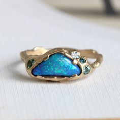 I love this luminous cloud-shaped boulder-opal, its glowing blue-green field filled with a confetti burst of sparkling lime green. A one of a kind 18k ring designed in our signature branch-style, with a hand-hammered texture and accents of natural blue spinel, afghanite and green tanzanite (aka fancy zoisite).  Organic minimalism with a brutalist vibe. It's designed to stand on its own as a unique statement, but it also mixes well with other pieces adding texture to your daily ring stack. Measur Unique Blue Multi-stone Opal Ring, Unique Green Opal Ring, Unique Blue Opal Ring, Organic Minimalism, Wax Carving Jewelry, Carving Jewelry, Boulder Opal Ring, Blue Spinel, Bohemian Bridal