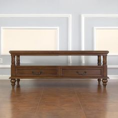 a large wooden coffee table sitting on top of a hard wood floor next to two framed pictures