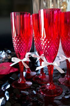 four red wine glasses with white bows on the rims are sitting next to each other