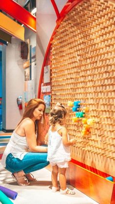 a mother and daughter playing with toys in a play area at the mall or museum