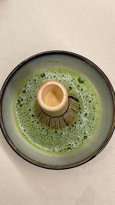 a green and black dish with a brush in the center on a white tablecloth