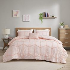 a bed in a bedroom with pink comforter and pillows