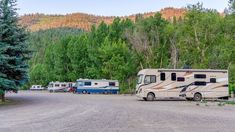 an rv park with several recreational vehicles parked on the side of the road and trees in the background